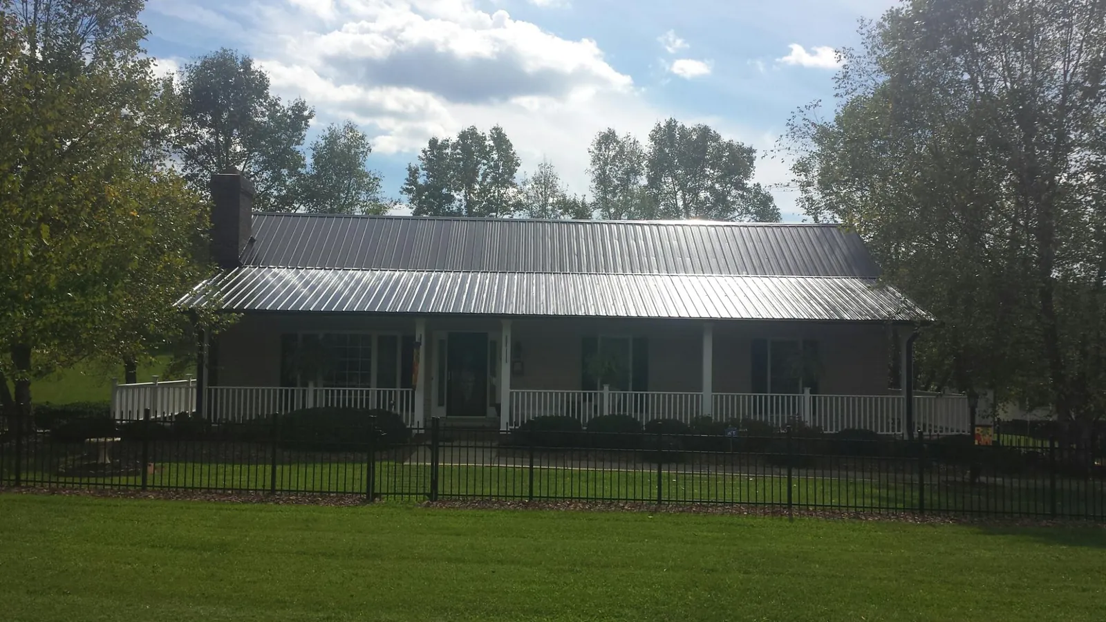 Gray metal roof on a brick ranch with a full width front porch — Gutter Guard Installation work by our crew in Boyd