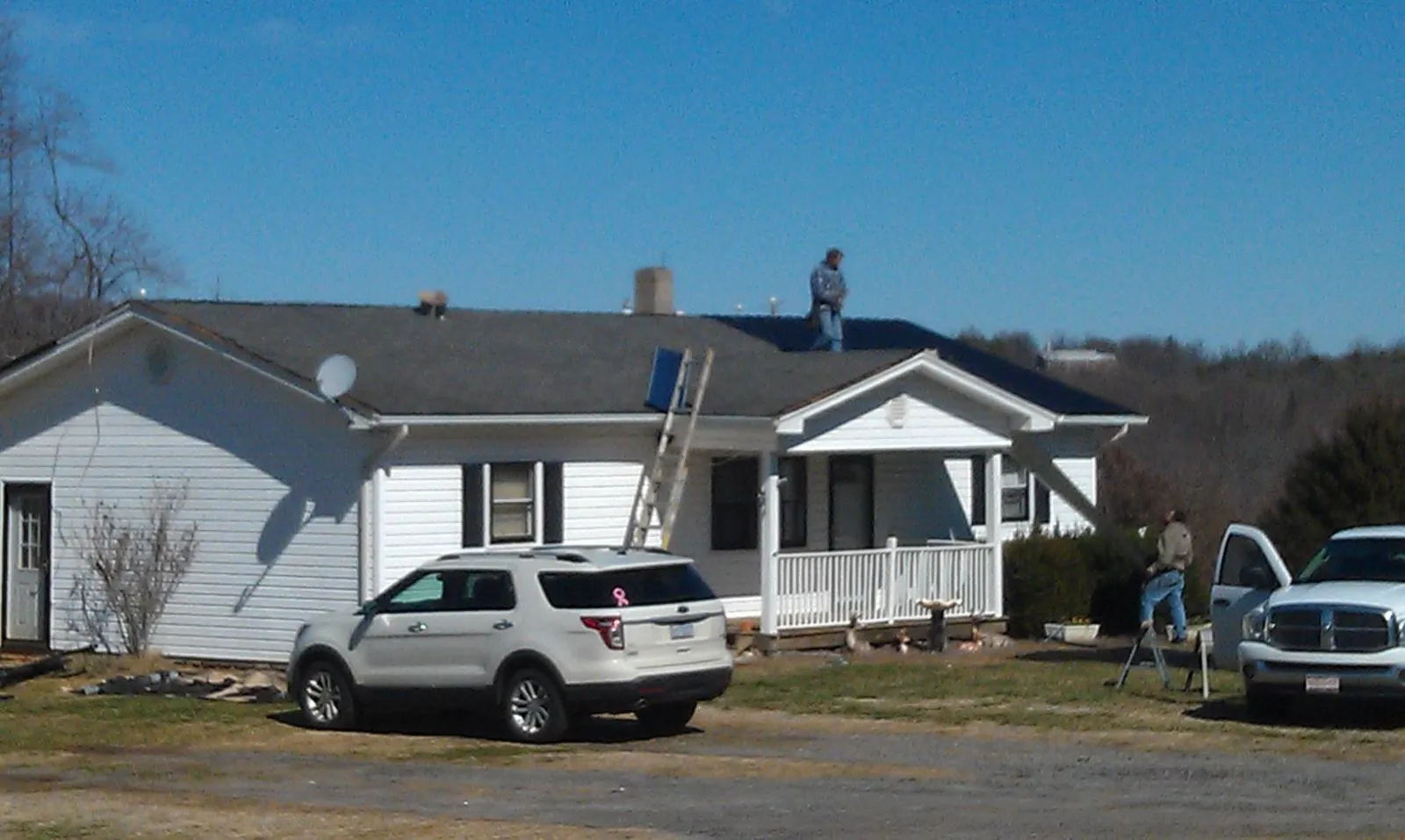 Roofers stripping shingles from a white ranch house roof in Boyd